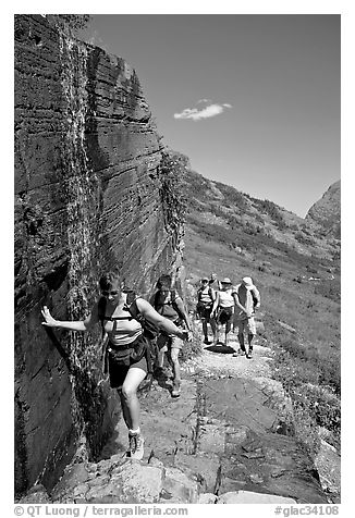 Walking under a small waterfall on the Grinnell Glacier trail. Glacier National Park, Montana, USA.