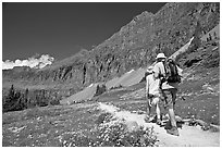 Hikers on trail amongst wildflowers near Hidden Lake. Glacier National Park, Montana, USA. (black and white)