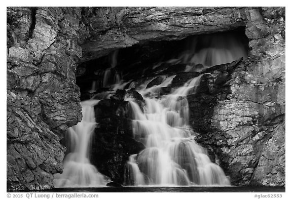 Water flows of opening in cliff face, Running Eagle Falls. Glacier National Park (black and white)