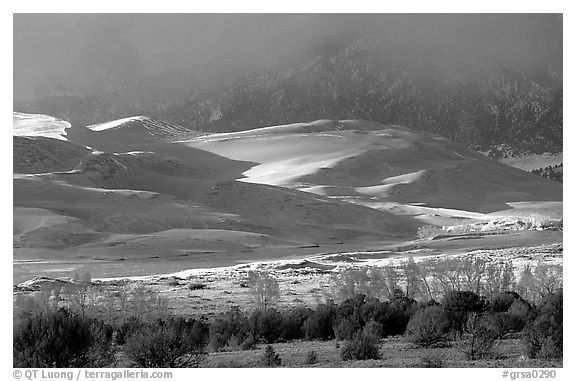 Storm light illuminates portions of the dune field. Great Sand Dunes National Park, Colorado, USA.