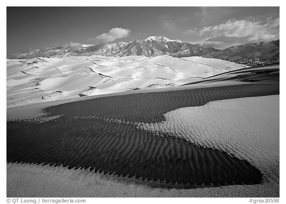 Patch of sand, snow-covered dunes, Sangre de Christo mountains. Great Sand Dunes National Park, Colorado, USA.