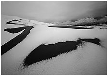 Patch of sand in snow-covered dunes. Great Sand Dunes National Park and Preserve ( black and white)