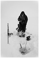 Man catching fish through hole in Jackson Lake ice. Grand Teton National Park, Wyoming, USA. (black and white)