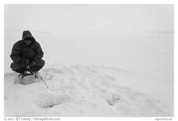 Man ice fishing on frozen Jackson Lake. Grand Teton National Park, Wyoming, USA.