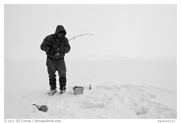 Ice fisherman standing next to hole, Jackson Lake. Grand Teton National Park, Wyoming, USA.