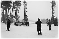 Tourists take pictures with entrance sign in winter. Yellowstone National Park, Wyoming, USA. (black and white)