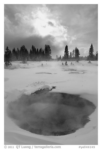 Thermal pool and dark clouds, winter. Yellowstone National Park, Wyoming, USA.