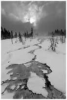 Colorful thermal stream and dark clouds, winter. Yellowstone National Park, Wyoming, USA. (black and white)