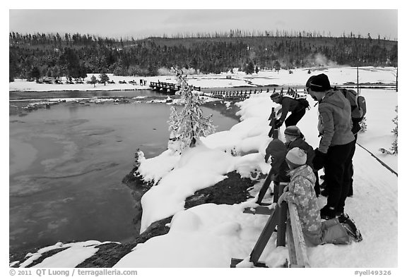 Family looks at thermal pool in winter. Yellowstone National Park, Wyoming, USA.