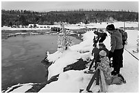 Family looks at thermal pool in winter. Yellowstone National Park, Wyoming, USA. (black and white)