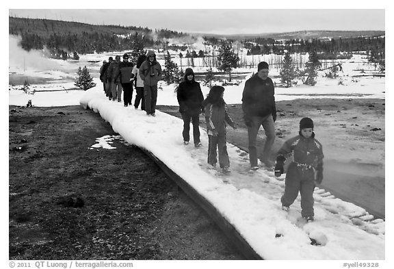 Tourists walk over snow-covered boardwalk. Yellowstone National Park, Wyoming, USA.