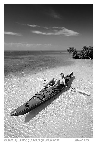 Woman sunning herself on sea kayak parked on shore,  Elliott Key. Biscayne National Park, Florida, USA.