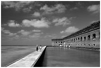 Tourists stroll on the seawall. Dry Tortugas National Park, Florida, USA. (black and white)