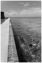 Snorkelers next to Fort Jefferson seawall. Dry Tortugas National Park, Florida, USA. (black and white)