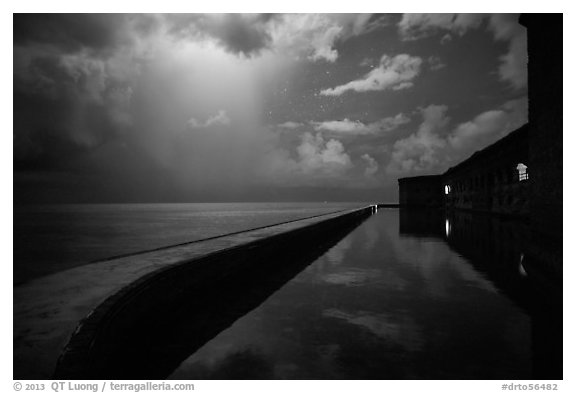 Fort Jefferson seawall at night with sky lit by tropical storm. Dry Tortugas National Park, Florida, USA.