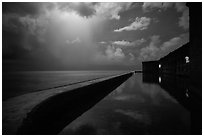 Fort Jefferson seawall at night with sky lit by tropical storm. Dry Tortugas National Park, Florida, USA. (black and white)