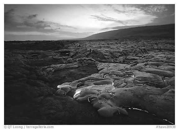 Volcanic landscape with molten lava flow and red spots at sunset. Hawaii Volcanoes National Park, Hawaii, USA.