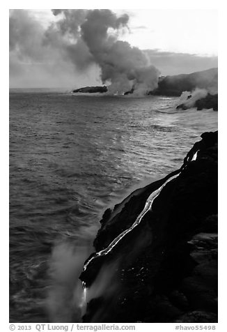 Bright molten lava flows into the Pacific Ocean, plume in background. Hawaii Volcanoes National Park, Hawaii, USA.