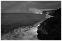 Streams of hot lava flow into the Pacific Ocean at the shore of erupting Kilauea volcano. Hawaii Volcanoes National Park ( black and white)