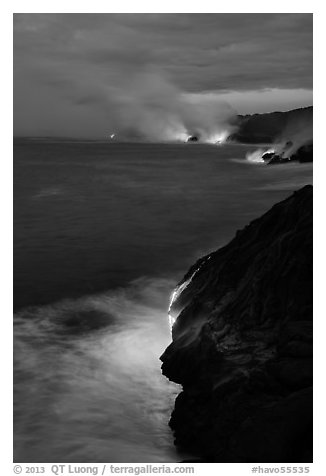 Molten lava pouring over sea cliffs at dawn. Hawaii Volcanoes National Park (black and white)