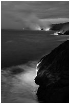 Molten lava pouring over sea cliffs at dawn. Hawaii Volcanoes National Park, Hawaii, USA. (black and white)
