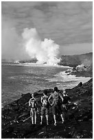 Hikers looking at molten lava and coastal volcanic steam cloud. Hawaii Volcanoes National Park, Hawaii, USA. (black and white)