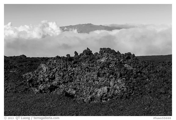 Black of colorful lava on Mauna Loa, Mauna Kea emerging from Saddle clouds. Hawaii Volcanoes National Park, Hawaii, USA.