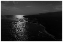 Aerial view of coastline with distant lava ocean entry and moonlight reflections at night. Hawaii Volcanoes National Park ( black and white)