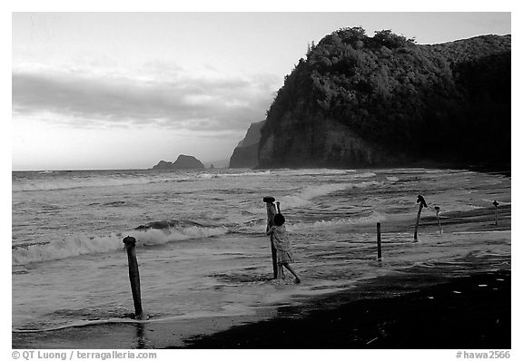 Hawaiian woman piling a stone on a stick as a gesture of reverence, Polulu Beach. Big Island, Hawaii, USA (black and white)