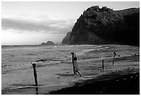 Hawaiian woman piling a stone on a stick as a gesture of reverence, Polulu Beach. Big Island, Hawaii, USA (black and white)