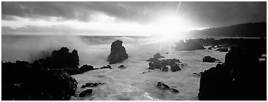 Primeval seascape with surf and rising sun. Maui, Hawaii, USA (Panoramic black and white)