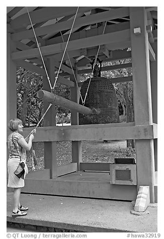 Tourist rings the sacred bell before entering Byodo-In temple. Oahu island, Hawaii, USA