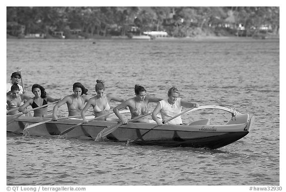 Outrigger canoe paddled by women in bikini, Maunalua Bay, late afternoon. Oahu island, Hawaii, USA (black and white)