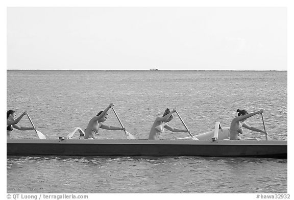 Side view of women in bikini paddling a outrigger canoe, Maunalua Bay, late afternoon. Oahu island, Hawaii, USA