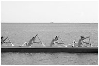 Side view of women in bikini paddling a outrigger canoe, Maunalua Bay, late afternoon. Oahu island, Hawaii, USA (black and white)