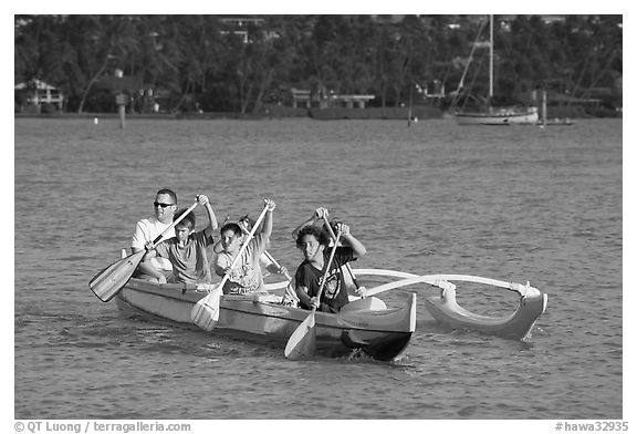 Boys paddling an outrigger canoe, Maunalua Bay, late afternoon. Oahu island, Hawaii, USA