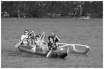 Boys paddling an outrigger canoe, Maunalua Bay, late afternoon. Oahu island, Hawaii, USA ( black and white)