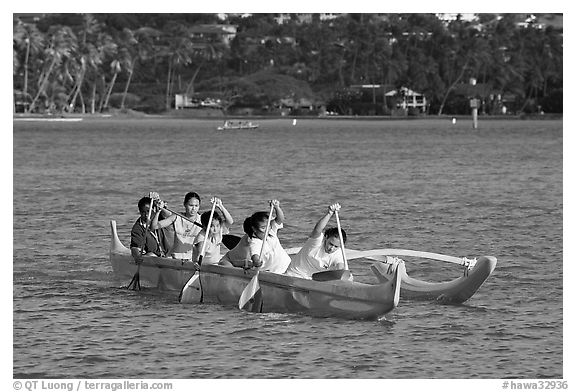 Girls paddling an outrigger canoe, Maunalua Bay, late afternoon. Oahu island, Hawaii, USA (black and white)