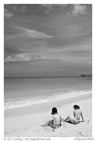 Young women sitting on Waimanalo Beach. Oahu island, Hawaii, USA (black and white)