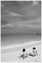 Young women sitting on Waimanalo Beach. Oahu island, Hawaii, USA (black and white)