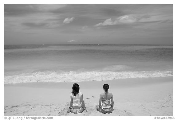 Young women facing the Ocean in a meditative pose on Waimanalo Beach. Oahu island, Hawaii, USA