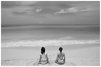 Young women facing the Ocean in a meditative pose on Waimanalo Beach. Oahu island, Hawaii, USA (black and white)