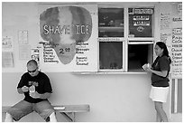 Shave ice store with man sitting eating and woman ordering, Waimanalo. Oahu island, Hawaii, USA ( black and white)