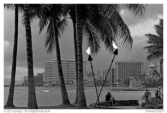 Waterfront at dusk with bare flame lamps. Waikiki, Honolulu, Oahu island, Hawaii, USA