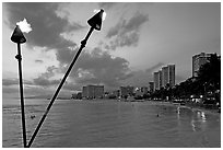 Bare flame torches and skyline at sunset. Waikiki, Honolulu, Oahu island, Hawaii, USA ( black and white)