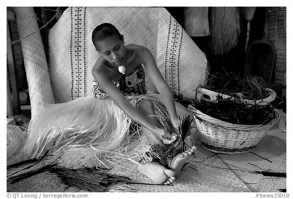 Fiji woman tying together leaves with her feet. Polynesian Cultural Center, Oahu island, Hawaii, USA