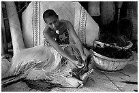 Fiji woman tying together leaves with her feet. Polynesian Cultural Center, Oahu island, Hawaii, USA (black and white)