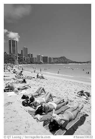 Young women on Waikiki Beach with skyline in the background. Waikiki, Honolulu, Oahu island, Hawaii, USA (black and white)