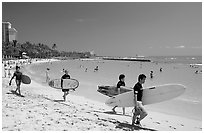 Men walking on Waikiki Beach with surfboards. Waikiki, Honolulu, Oahu island, Hawaii, USA (black and white)