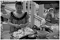 Woman preparing a fresh flower lei, with another woman looking, International Marketplace. Waikiki, Honolulu, Oahu island, Hawaii, USA ( black and white)